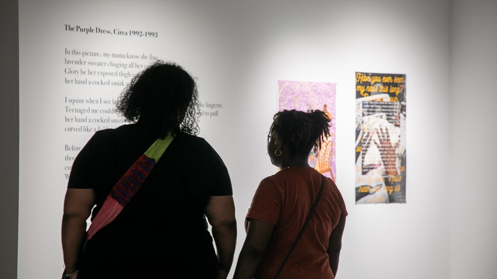 Two women looking at poetry and artwork.