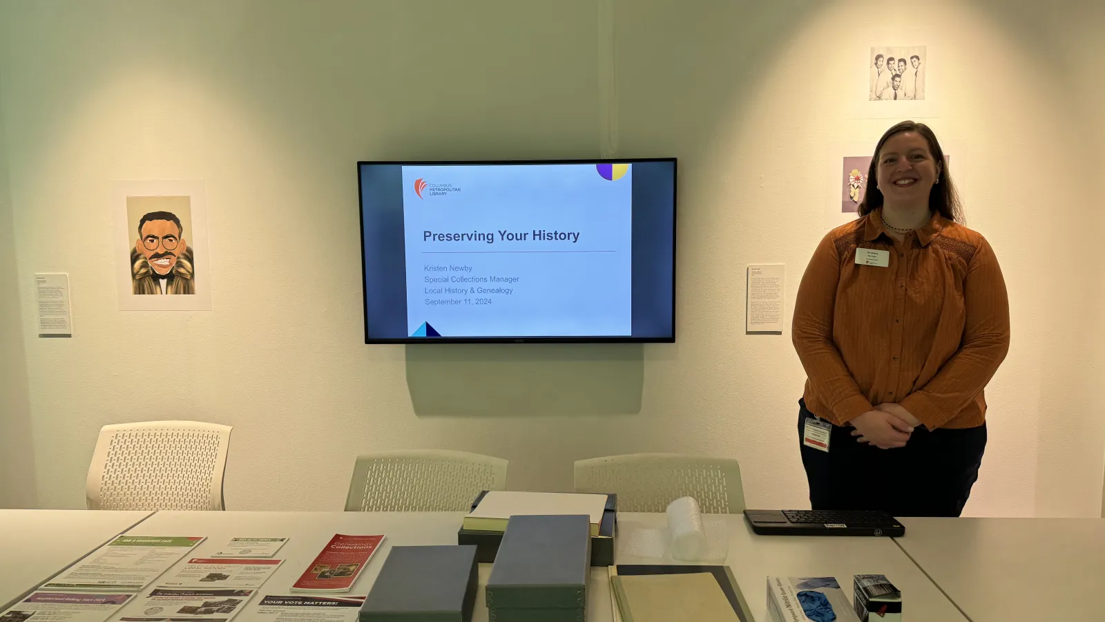 Librarian smiling next to a powerpoint on preserving your history