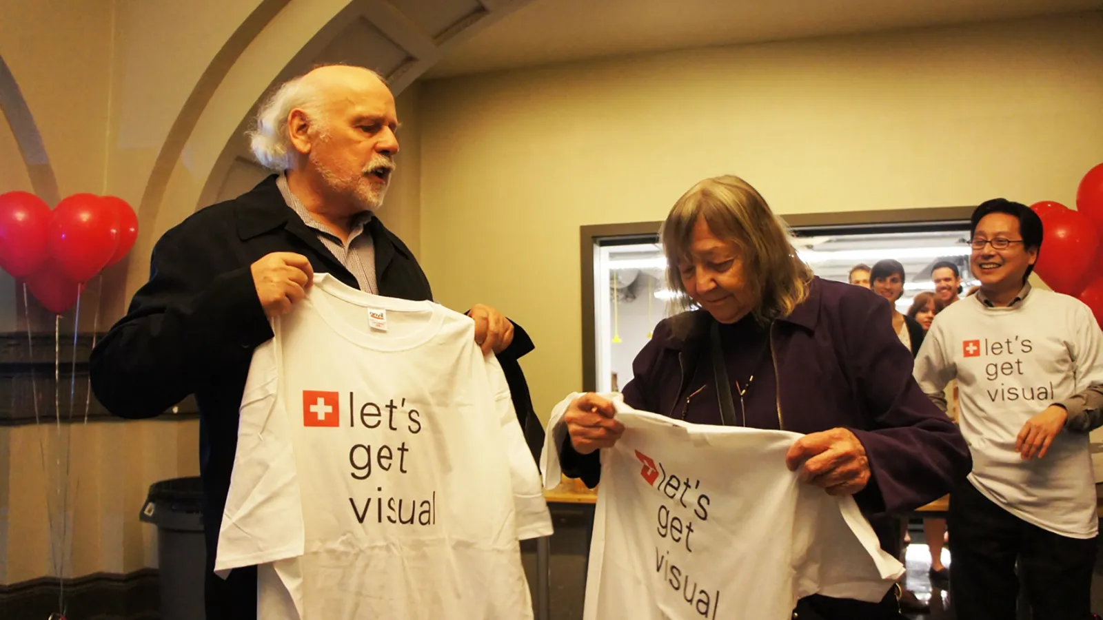 Peter and his wife Ursula holding up shirts that say let's get visual