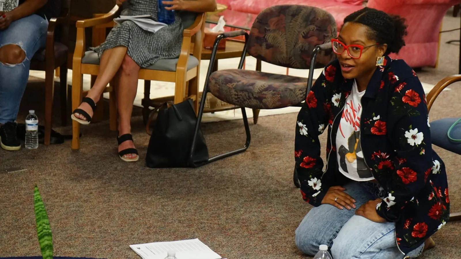 Ajanae kneeling on the floor with papers