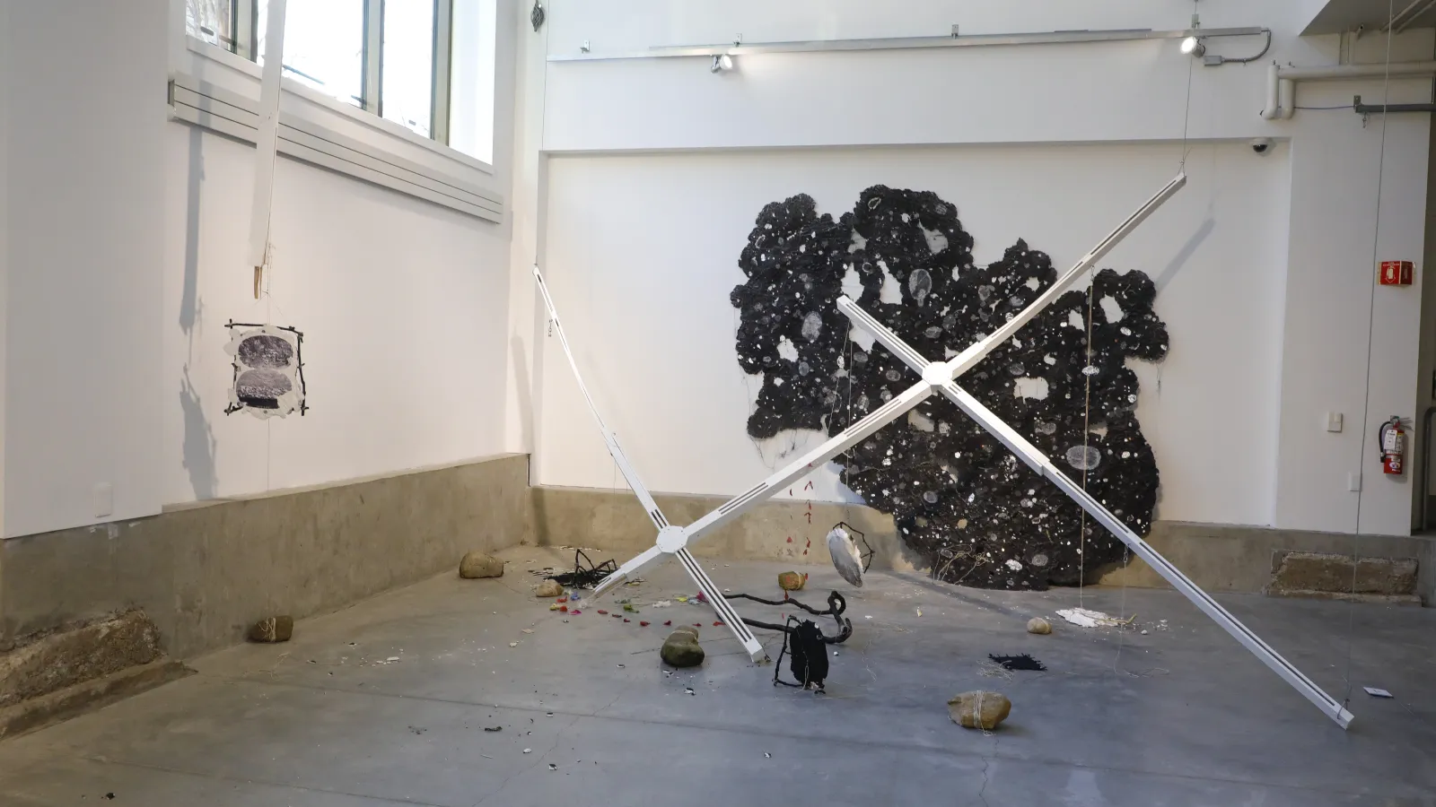Large installation piece with black material on a wall and fallen pieces of sculpture on the ground