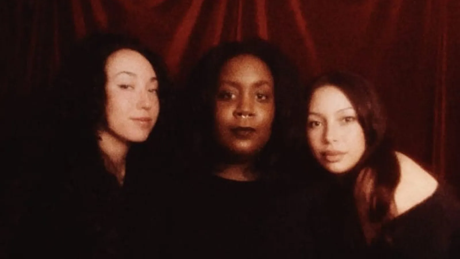 three curators for the show against a velvet backdrop