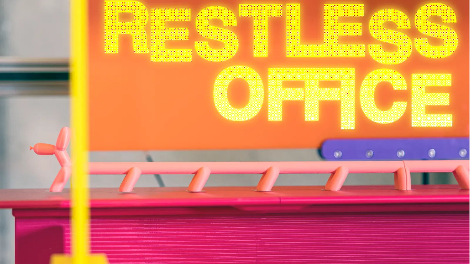 Yellow text that says Restless Office over a close up of pink and purple plastic pieces, including what looks like a long dog balloon animal