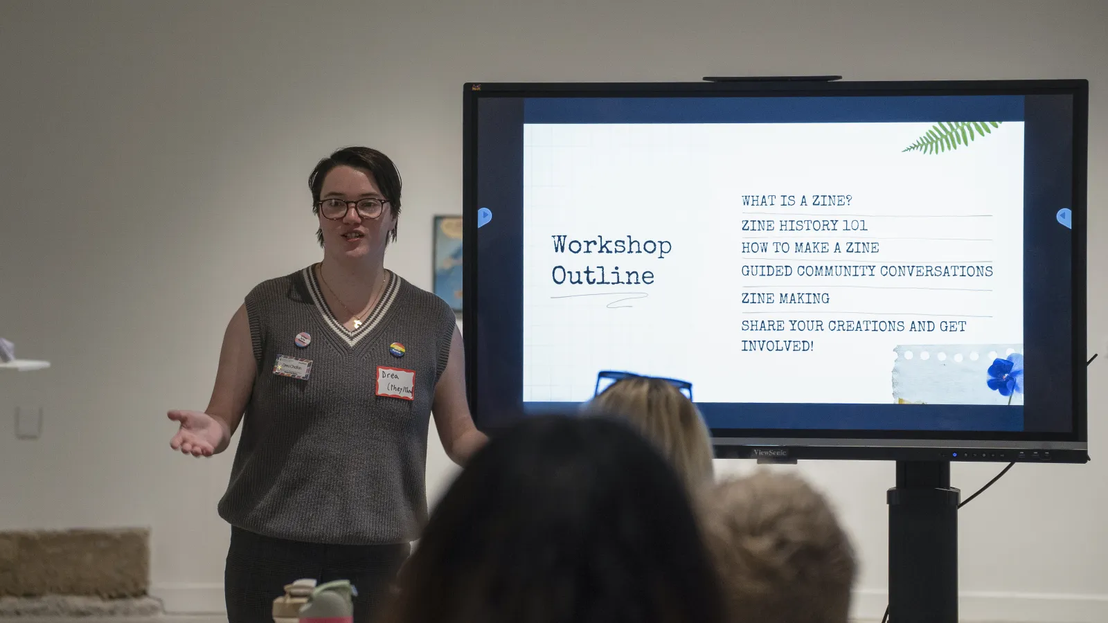 Drea presents and speaks to crowd in front of a screen containing a workshop outline