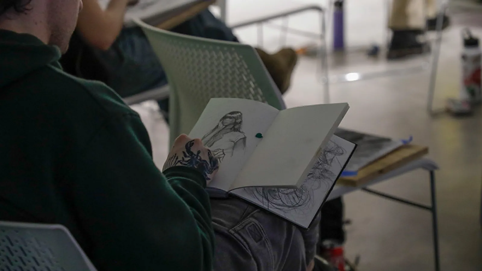 Individual sketching a woman in their notebook
