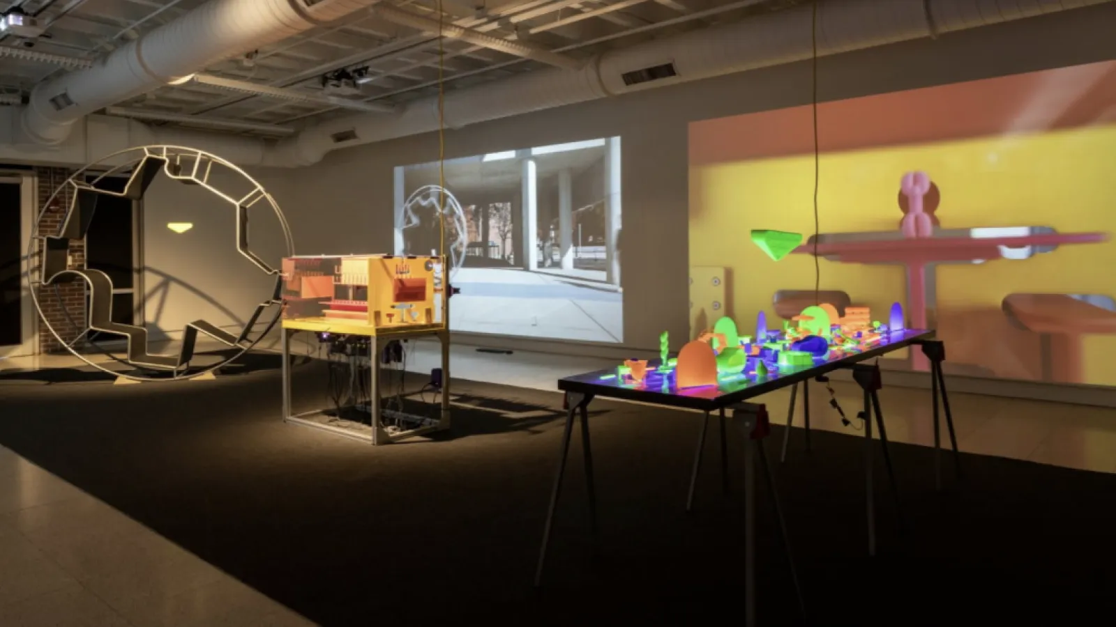 hopkins hall gallery with architectural installations, such as a large wheel and a table of small office furniture replicas