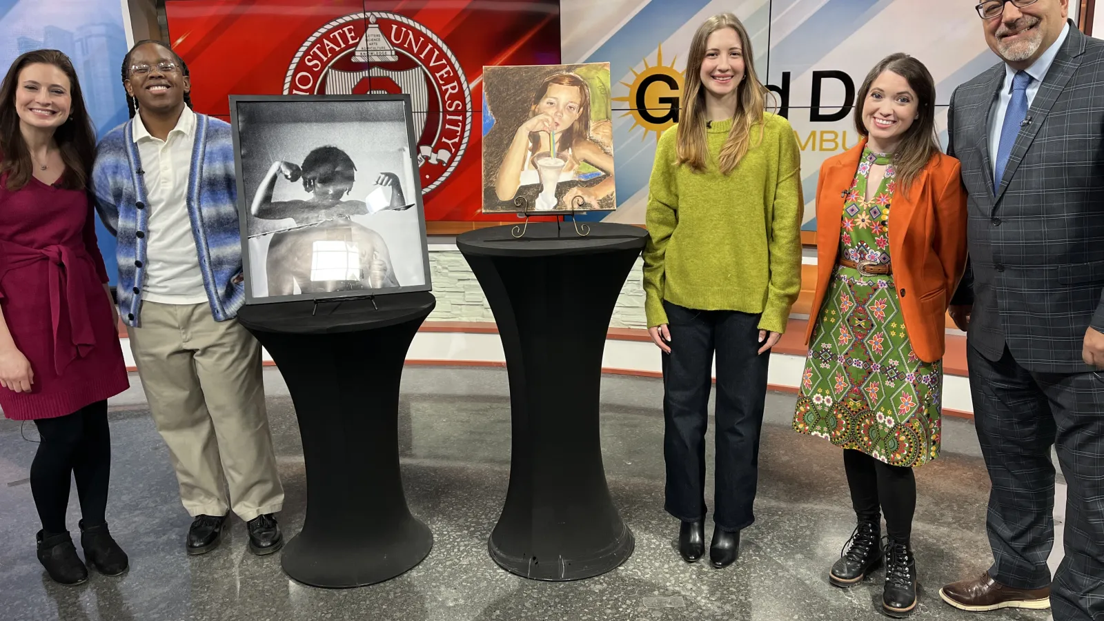 student artists and news anchors stand and smile in the newsroom