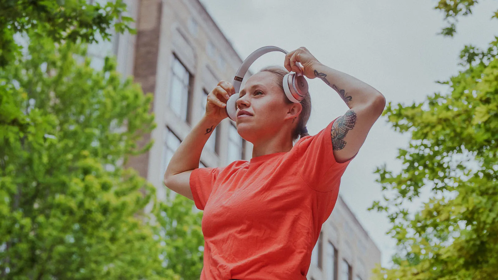 Woman standing outside while holding headphones just above the ears
