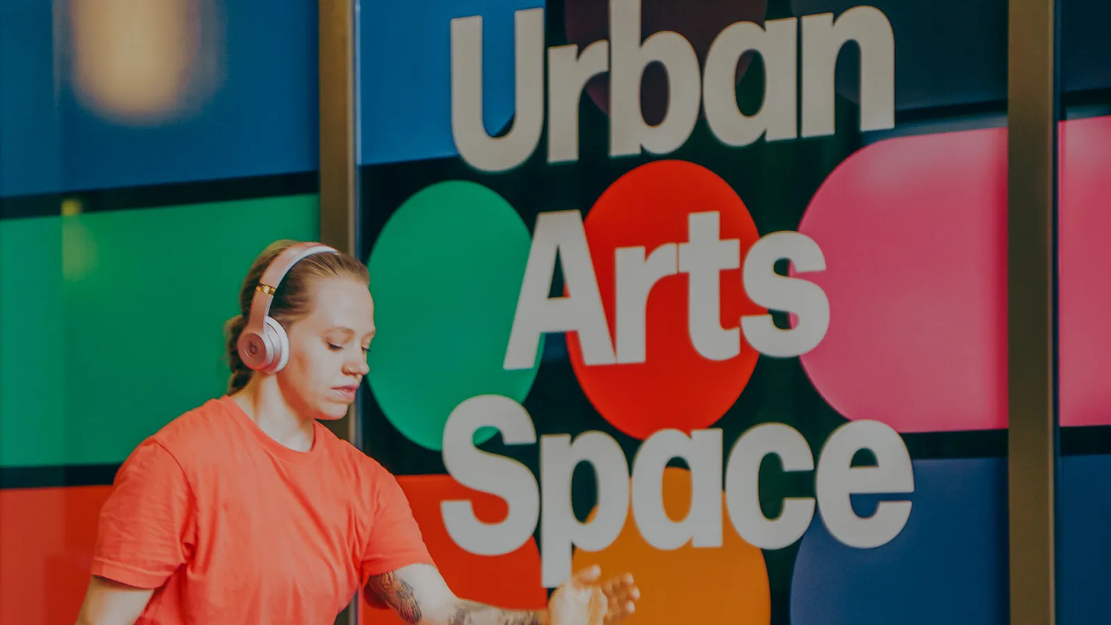 Woman with headphones on walking outside of Urban Arts Space