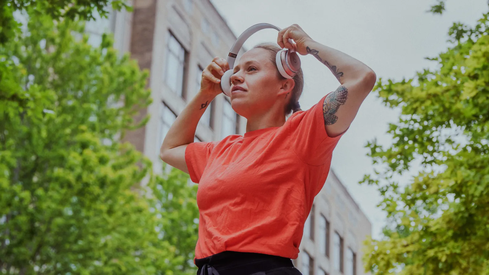 Woman standing outside putting headphones onto her head