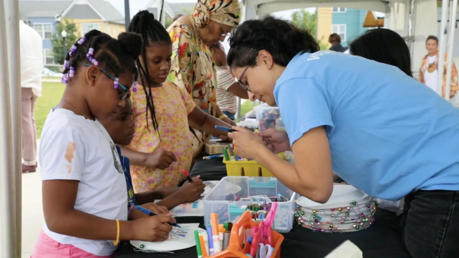 worker helping three kids with a craft