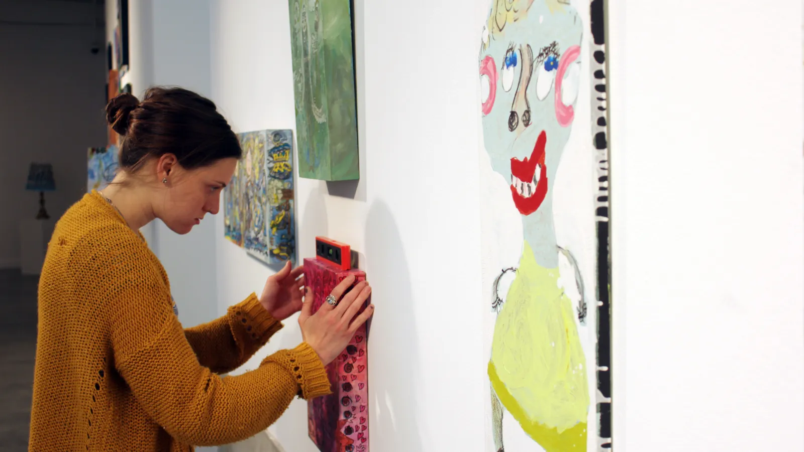 An intern hangs a painting on a wall.