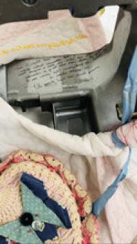 An aerial view of part of the assemblage. A corner of the sewing machine and colorful stitched fabric with a bow are visible.