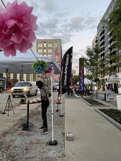 Arris' painting at the event with paper flowers hanging overhead