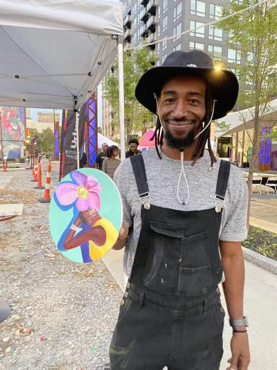 Arris' holding up his painting of a woman with a flower head