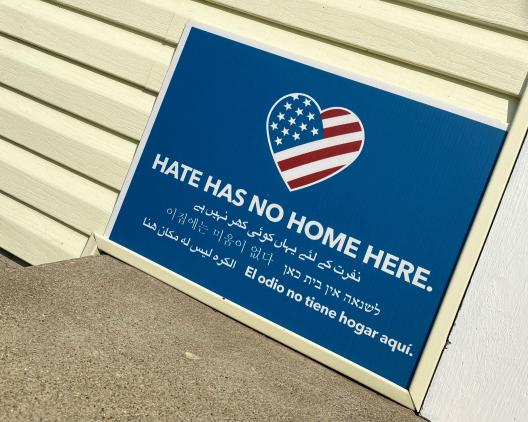 sign against yellow house that says, Hate Has No More Here" in several languages