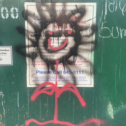 graffiti smiley face on garbage bin 