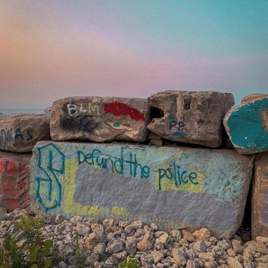 graffiti on boulder that says, "Deund the Police"