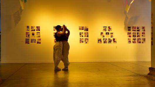 Two dancers dancing with each other in front of a wall with photos