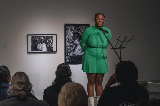 Ajanae in a green dress reading into the mic