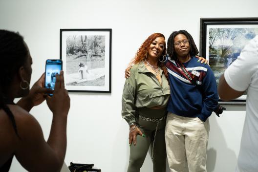 Two artists smiling in front of photographs at the gallery