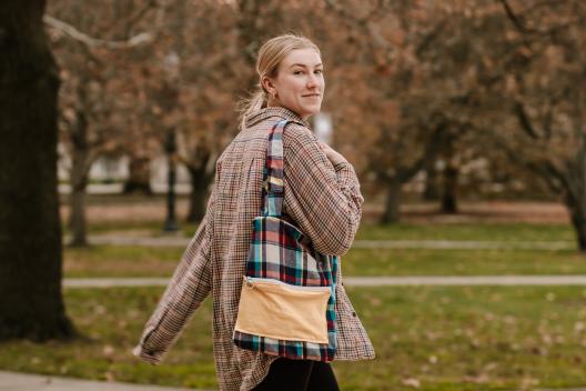 A model looks at the camera while walking and carrying a Tee Tote.