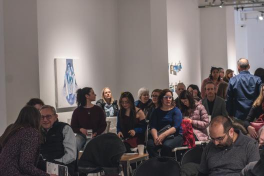 Crowd of seated visitors at a poetry reading