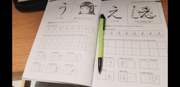 open Japanese textbook with green pen