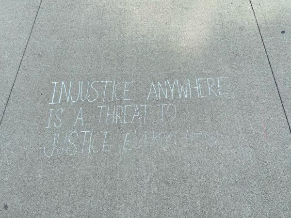 "Injustice Anywhere is a Threat to Justice Everywhere" written in chalk on sidewalk 