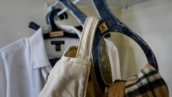 Lambda hangers hang in a closet holding a shirt and bags.
