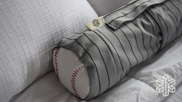 A gray cylindrical bag with a handle on top and an image of a baseball at one end