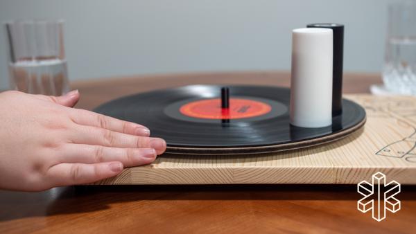 Salt and pepper shakers sit on top of the record while a person holds their hand on it, as if to spin it.