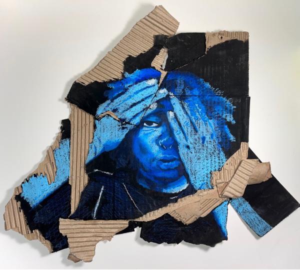 A person painted in blue covering their face with their hands on cardboard