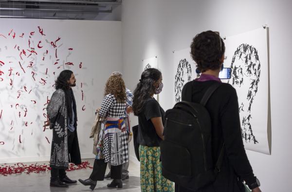 Illya and three visitors examining the artwork at Urban Arts Space