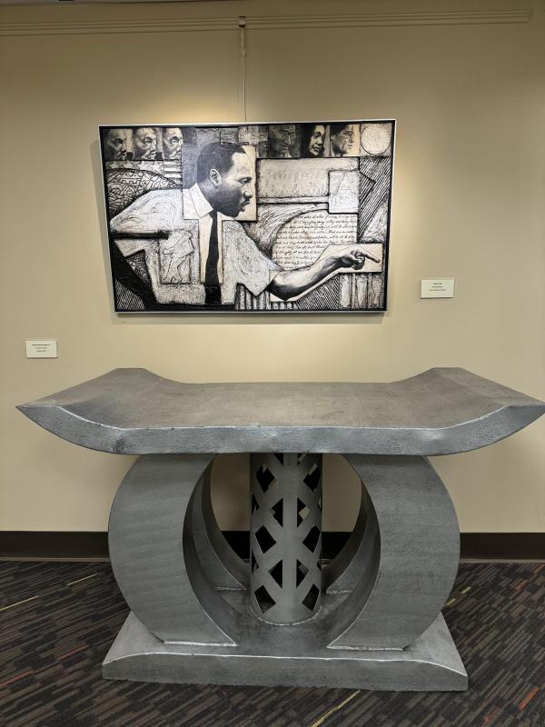 Painting of MLK with a silver bench-shaped sculpture beneath