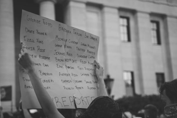 protester holding sign depicting names of those killed by police