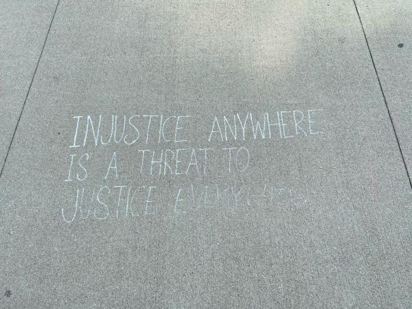 "Injustice Anywhere is a Threat to Justice Everywhere" written in chalk on sidewalk 