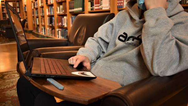 A model sits with a laptop on top of their MANU Board.