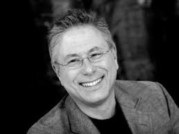 A photograph of Alan Menken, smiling into the camera