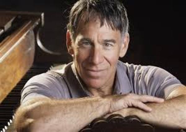 A photograph of Steven Schwartz, smiling into the camera with arms folded