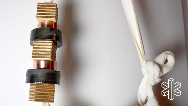 A close-up image of copper pieces and cream-colored string tied in a knot