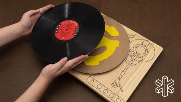 A person places the record on top of the wood board.