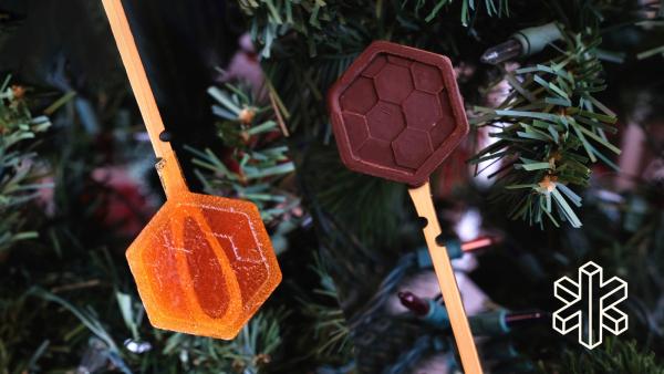 A bamboo stick with an orange hexagon topper and a bamboo stick with a brown hexagon topper
