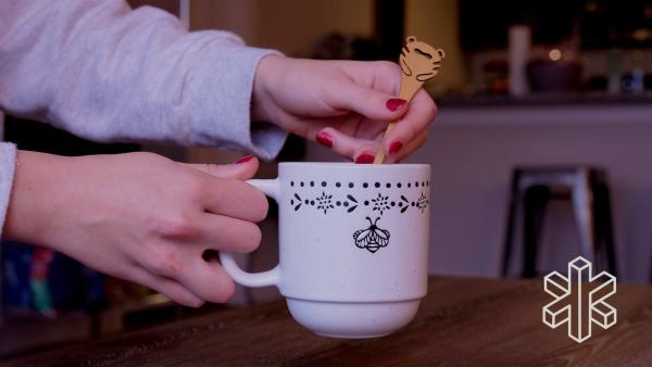 A close-up of a person holding a Lollihop inside a white mug