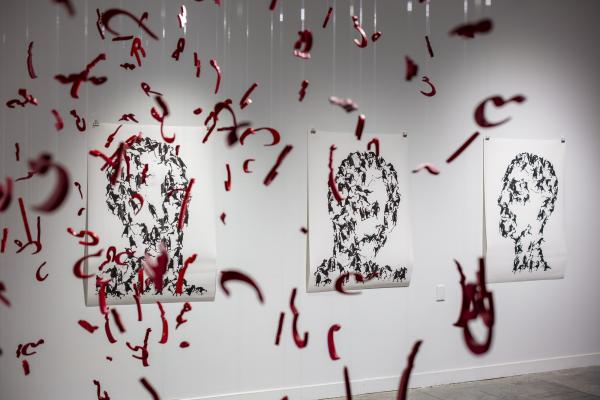 Hanging red letters in Farsi in front of three portraits of people composed of fighting individuals