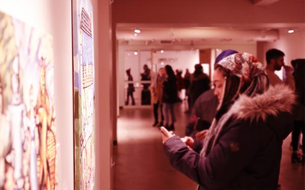 A young woman stands in front of an art display in a gallery