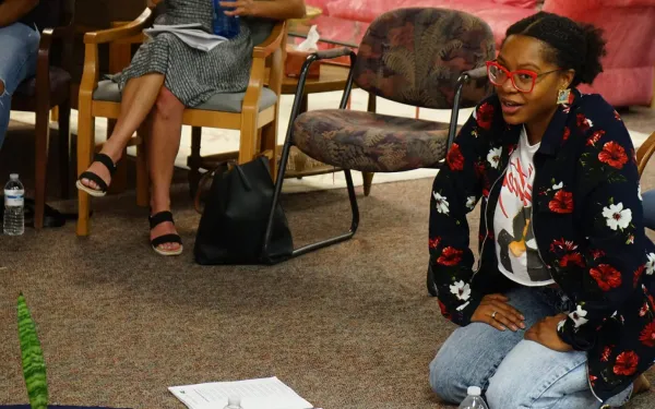 Ajanae kneeling on the floor with papers