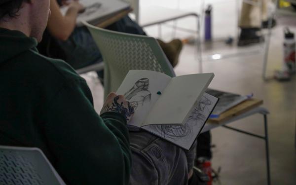 Individual sketching a woman in their notebook