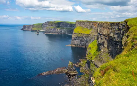 A grassy cliffside overlooking clear blue water