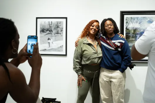 Two artists smiling in front of photographs at the gallery